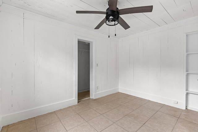 spare room with light tile patterned flooring, wooden walls, and ceiling fan