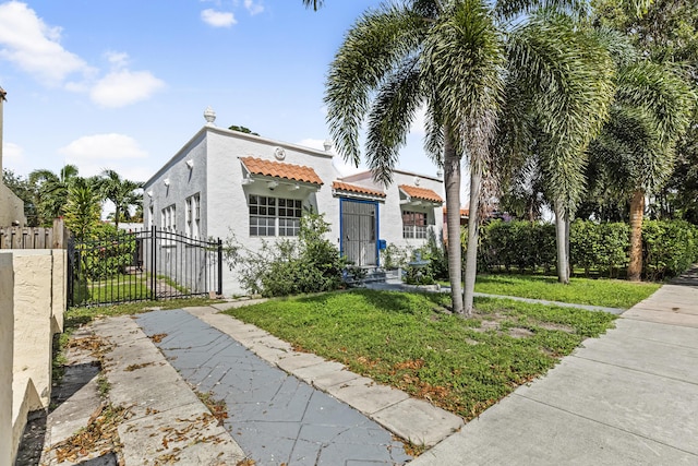 435 35th St, West Palm Beach, FL 33407 - mediterranean / spanish-style home with a tile roof, a gate, stucco siding, fence, and a front lawn