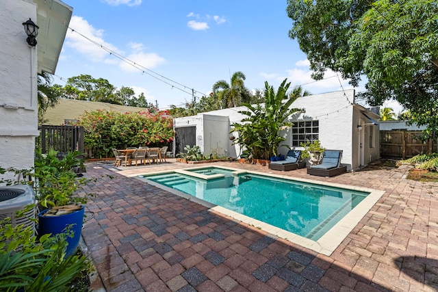 view of pool featuring an in ground hot tub, a shed, and a patio