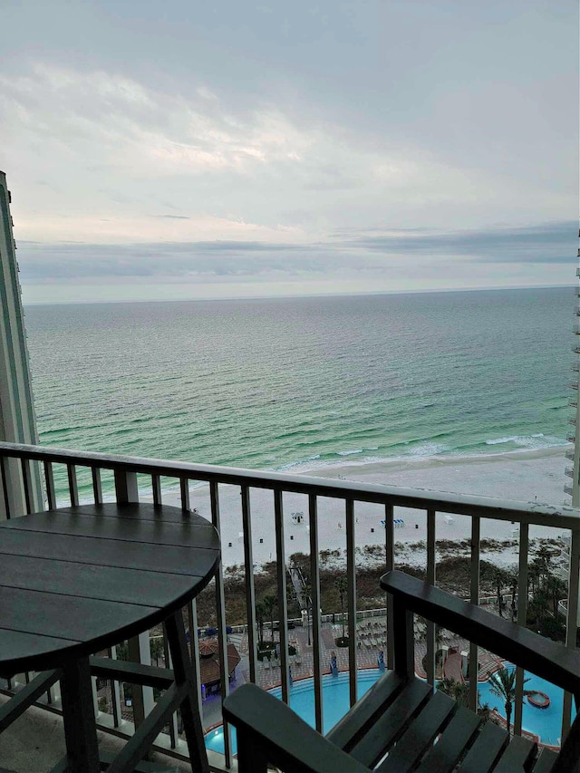 balcony featuring a water view, a beach view, and a community pool