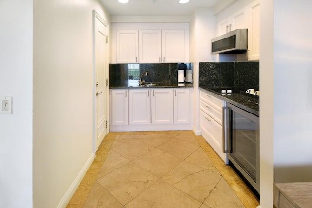 kitchen with tasteful backsplash, dark stone countertops, white cabinetry, and wine cooler