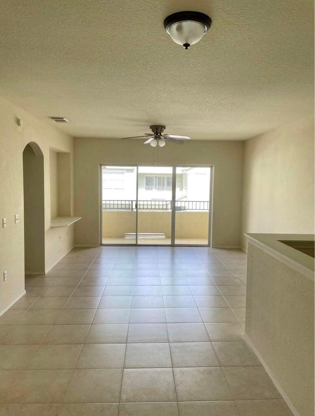 tiled empty room featuring a textured ceiling and ceiling fan