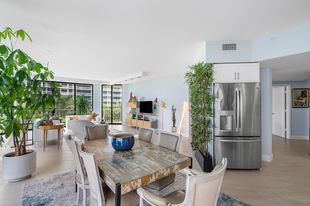 dining space with expansive windows, baseboards, visible vents, and light wood finished floors