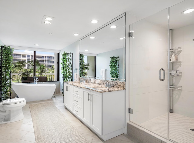 bathroom featuring recessed lighting, a soaking tub, toilet, a stall shower, and vanity