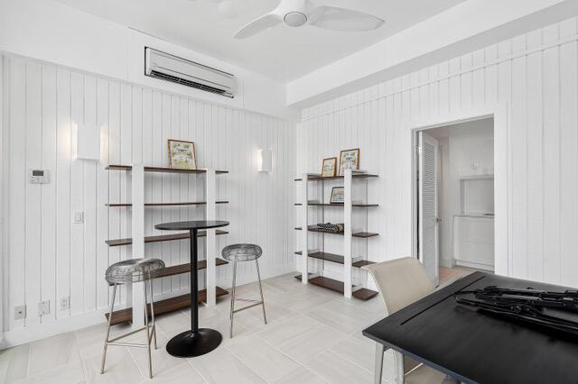 interior space with tile patterned flooring, a ceiling fan, and a wall mounted air conditioner