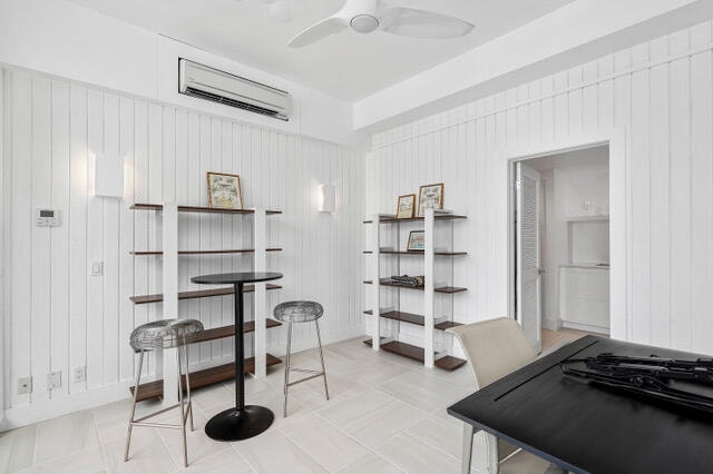 dining area featuring wood walls, a wall unit AC, and ceiling fan