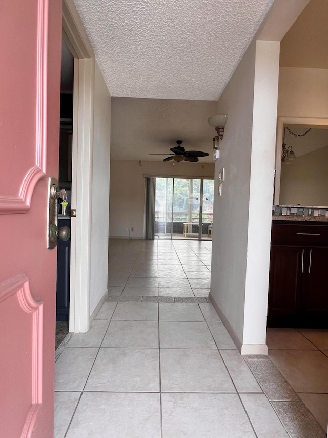 hallway with a textured ceiling and light tile patterned floors