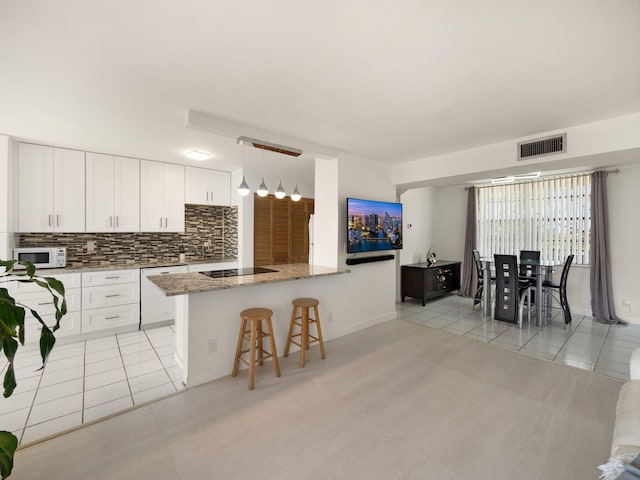 kitchen with white cabinetry, hanging light fixtures, white appliances, and light tile patterned floors