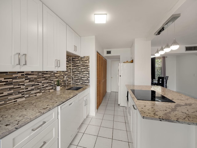 kitchen featuring tasteful backsplash, white appliances, light stone countertops, hanging light fixtures, and sink