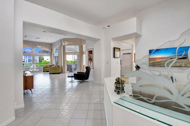 interior space with a ceiling fan, baseboards, and light tile patterned floors