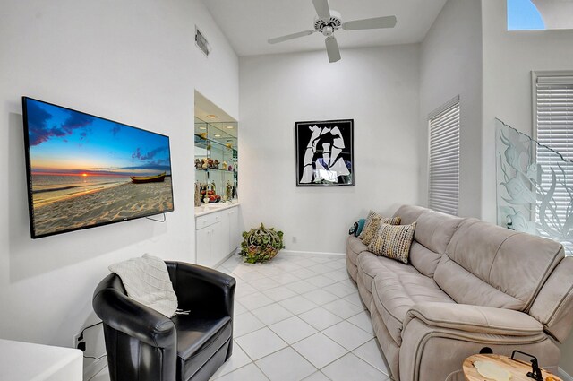 living area with light tile patterned floors, ceiling fan, visible vents, and baseboards