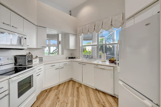 kitchen with plenty of natural light, white cabinetry, light hardwood / wood-style flooring, and white appliances