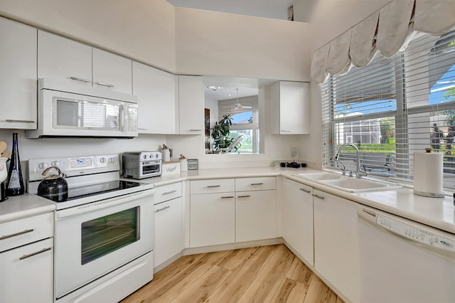 kitchen with sink, light hardwood / wood-style flooring, white appliances, and white cabinets