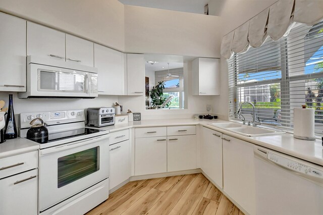 kitchen with light countertops, white appliances, a sink, and white cabinetry