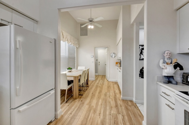 kitchen featuring white cabinetry, white fridge, ceiling fan, light hardwood / wood-style floors, and vaulted ceiling