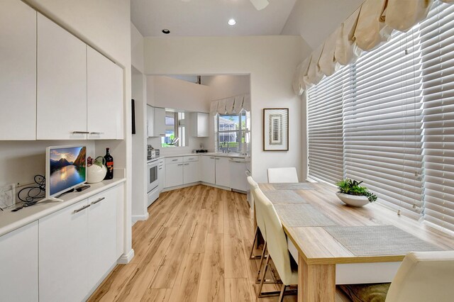 kitchen with light wood finished floors, white cabinets, light countertops, white electric range, and a sink