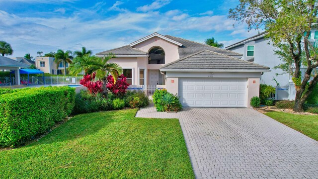 view of front of home featuring an attached garage, fence, decorative driveway, stucco siding, and a front lawn