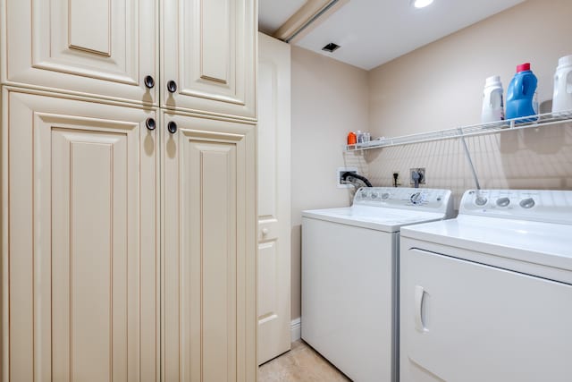 laundry area with light tile patterned flooring, cabinets, and independent washer and dryer