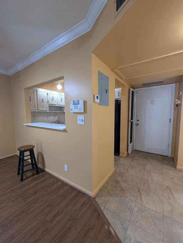 hallway with electric panel, light hardwood / wood-style flooring, and ornamental molding