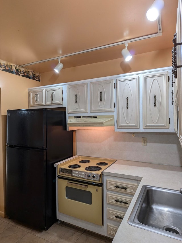 kitchen featuring rail lighting, white range with electric cooktop, black refrigerator, and light tile patterned flooring