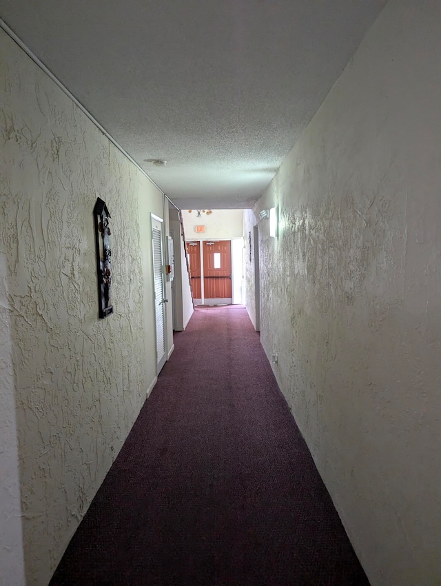 hall with a textured ceiling and carpet floors