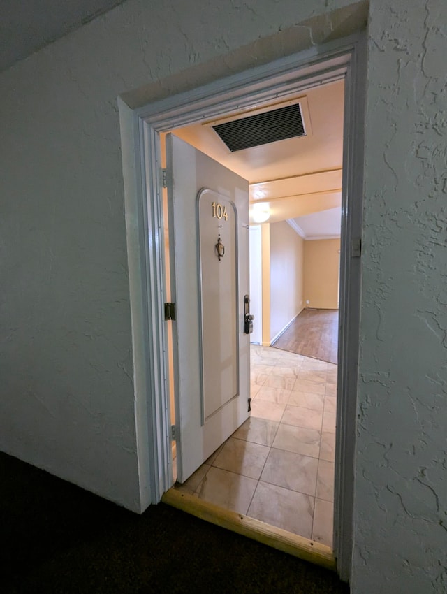 corridor with light hardwood / wood-style floors and crown molding