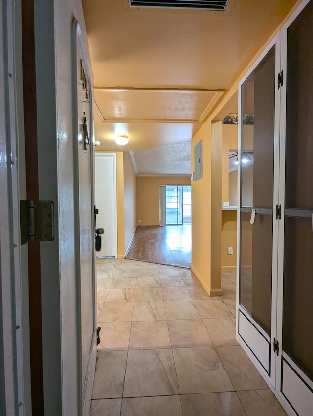 hallway featuring electric panel, ornamental molding, and light tile patterned floors