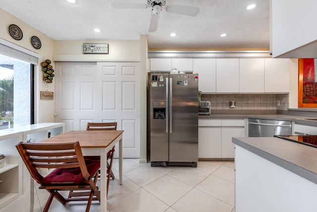 kitchen featuring light tile patterned flooring, appliances with stainless steel finishes, white cabinets, decorative backsplash, and ceiling fan