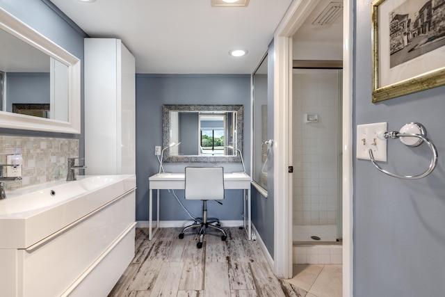 bathroom with tasteful backsplash, hardwood / wood-style floors, vanity, and walk in shower