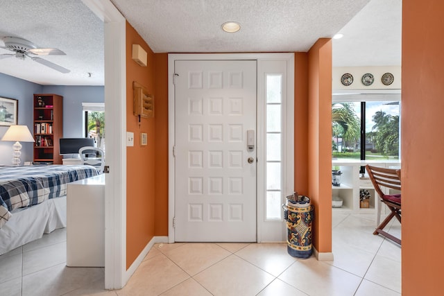 foyer entrance featuring a textured ceiling, ceiling fan, and light tile patterned flooring