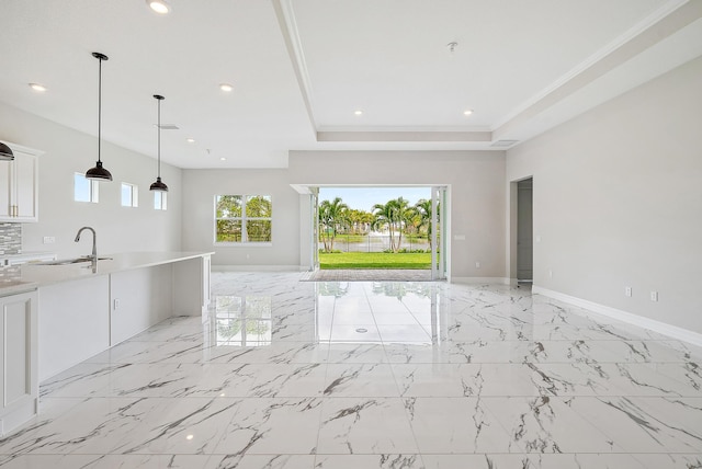 unfurnished living room featuring sink, a raised ceiling, and light tile patterned floors