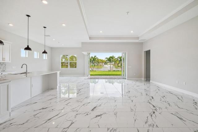 unfurnished living room with ornamental molding, sink, and a raised ceiling