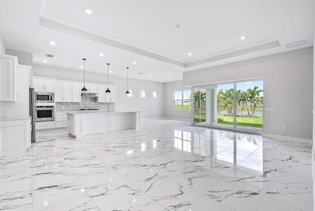 kitchen with a kitchen island with sink, white cabinetry, decorative light fixtures, and appliances with stainless steel finishes