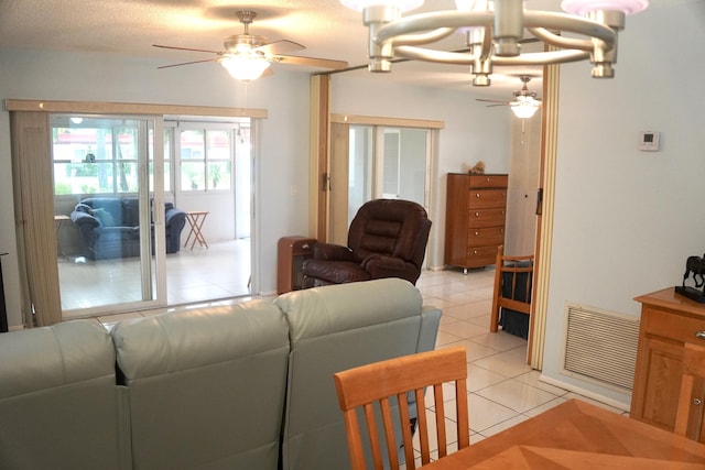 living room featuring visible vents, light tile patterned flooring, and ceiling fan with notable chandelier