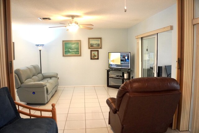 living room featuring ceiling fan, light tile patterned flooring, and a textured ceiling