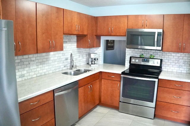 kitchen with light tile patterned floors, sink, appliances with stainless steel finishes, and tasteful backsplash