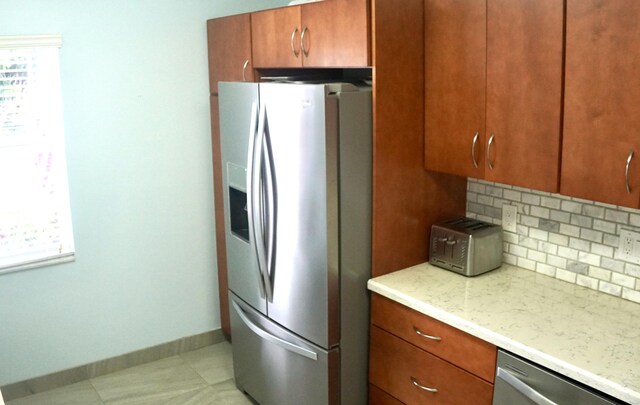 kitchen featuring light stone counters, appliances with stainless steel finishes, and tasteful backsplash