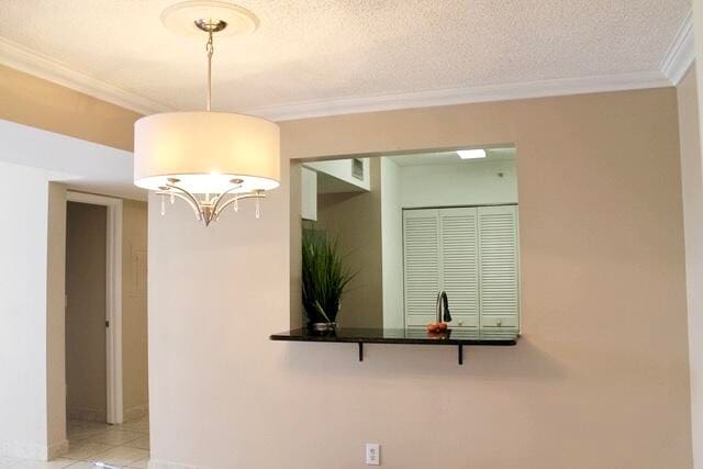 kitchen with a notable chandelier, light tile patterned floors, a textured ceiling, and ornamental molding