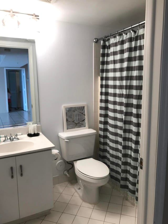 bathroom with toilet, vanity, and tile patterned flooring