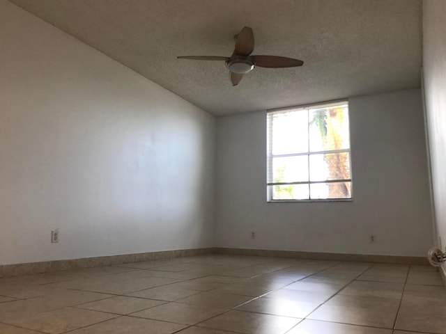 unfurnished room featuring a textured ceiling, lofted ceiling, light tile patterned floors, and ceiling fan