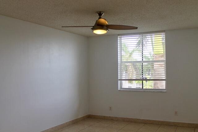 tiled spare room featuring ceiling fan and a textured ceiling