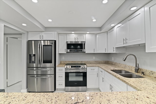 kitchen featuring white cabinetry, appliances with stainless steel finishes, sink, and light stone counters