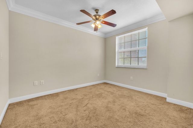 empty room with carpet, ornamental molding, ceiling fan, and baseboards