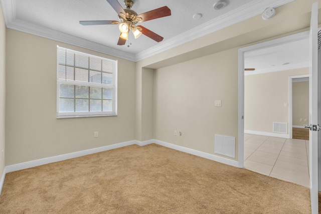 carpeted empty room with ornamental molding, visible vents, ceiling fan, and baseboards