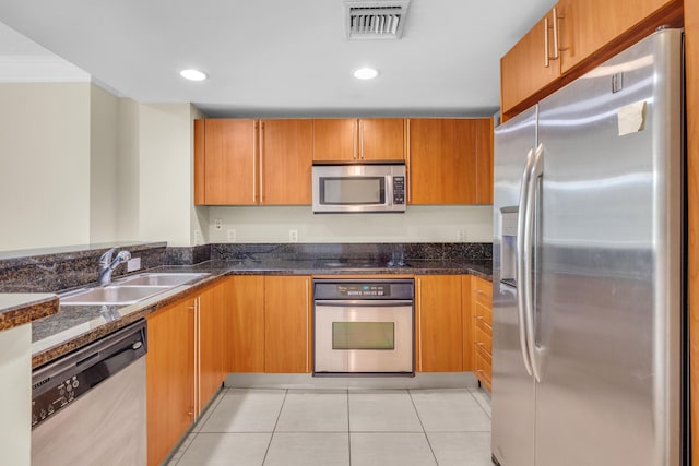 kitchen with visible vents, dark stone counters, stainless steel appliances, a sink, and light tile patterned flooring