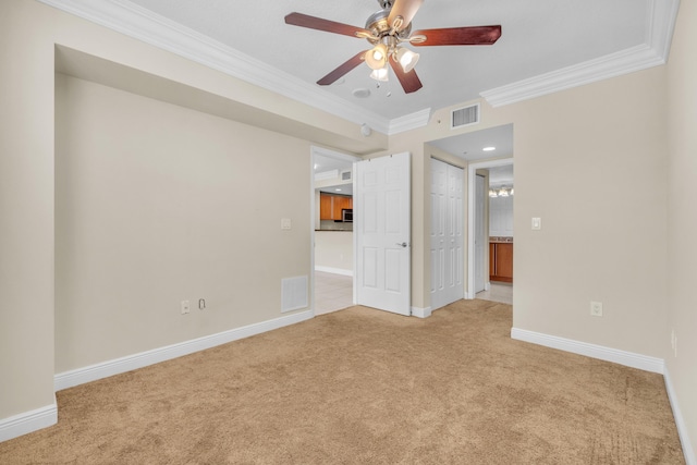 spare room with baseboards, visible vents, a ceiling fan, light colored carpet, and crown molding