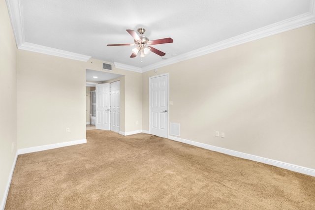 carpeted empty room with ceiling fan, visible vents, baseboards, and ornamental molding