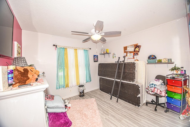 bedroom with light wood finished floors, a textured ceiling, baseboards, and a ceiling fan