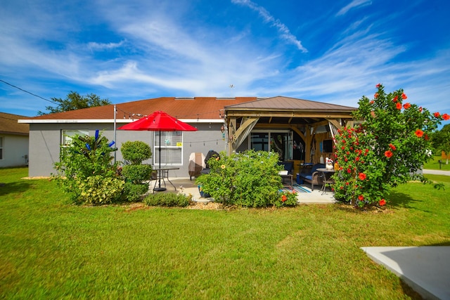 back of house with a gazebo, a patio, a lawn, and stucco siding