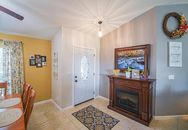 foyer featuring light tile patterned floors, plenty of natural light, baseboards, and a glass covered fireplace